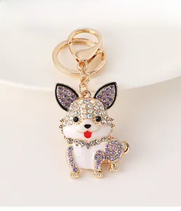 Detail of cute dog keychain with gold alloy finish, purple rhinestones and white enamel