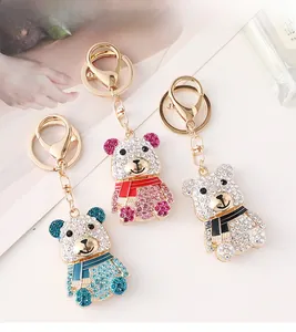 Trois porte-clés ours incrustés de strass avec des écharpes colorées sur un magazine
