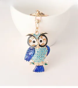 Close-up of golden owl keychain featuring blue rhinestones and detailed enamel wings