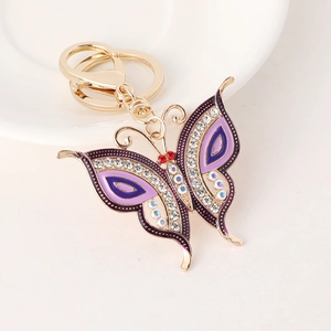 Sparkly purple butterfly keychain with crystals and gold lobster clasp on white surface