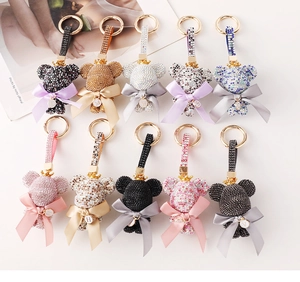 Multiple colorful rhinestone bear keychains with bows and golden letter charms