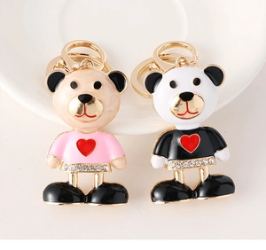 Close-up of bear keychains with rhinestone belts and heart patterns on a white dish