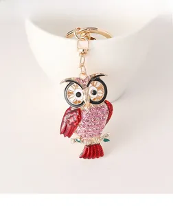Close-up of owl keychain with pink rhinestones on a white cup with gold metal clasp