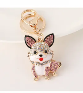 Detail of cute dog keychain with pink rhinestones and white enamel on golden alloy