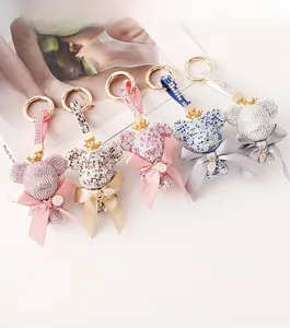 Close-up of assorted rhinestone bear keychains with gold letter charms and silk bows