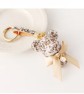 Macro detail of rhinestone bear keychain with gold crown, silk bow and letter H tag