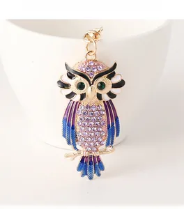 Detailed view of colorful crystal owl keychain with enamel wings on white ceramic cup