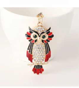 Detail of owl keychain featuring white rhinestones, green crystal eyes and red enamel art