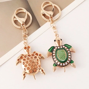 Porte-clés tortue dorée avec émail vert et strass montrant les deux faces de l'objet