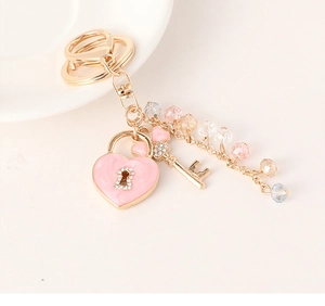 Detailed macro shot of pink enamel heart lock keychain with crystal inlay and gold key charms