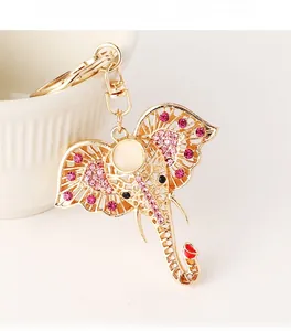 Detailed view of gold elephant keychain with pink rhinestones on a white ceramic cup