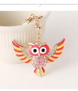 Détail du porte-clés hibou avec strass roses et ailes émaillées sur une tasse blanche
