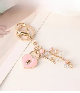 Detail showing pink enamel heart lock, gold key, and colorful crystal bead chain