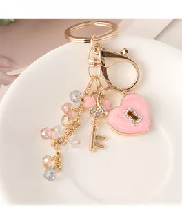 Detail of pink enamel heart lock and crystal-beaded keychain on a ceramic tray