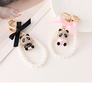 Close-up of pearl panda keychain with ribbon bow and crystal pendant on white background