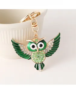 Détail du porte-clés hibou avec strass verts et métal doré sur une tasse blanche