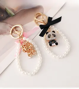Close-up of cute panda keychain with pearls, pink bow, and glittering crystal details