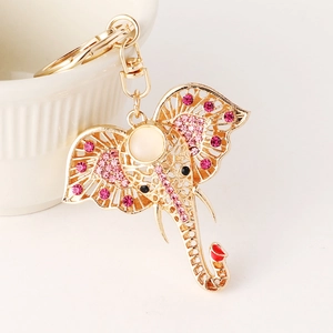 Golden elephant keychain with pink rhinestones and white stone on a white background