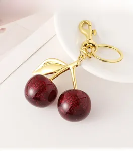 Detail of red glitter cherry keychain with gold metal stem and spring hook