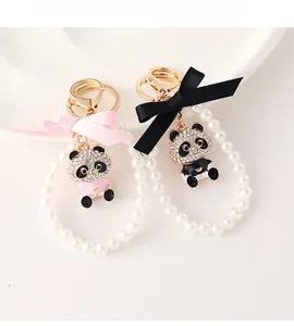 Close-up of sparkling panda charms with pearls and silk bows on white ceramic
