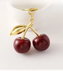 Close-up of glittery red double cherry keychain with golden metal leaf and ring details