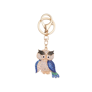 Porte-clés hibou doré avec cristaux scintillants et détails en émail bleu sur blanc