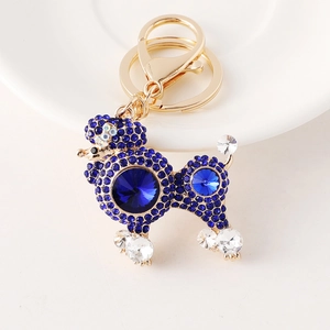 Luxurious gold-tone Poodle keychain with dark blue crystals on a white ceramic plate