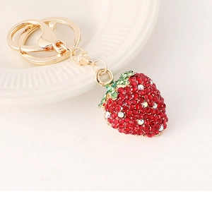 Gros plan du porte-clés fraise serti de strass rouges et verts avec crochet doré