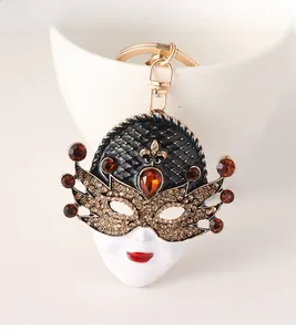 Detail of masquerade mask keychain with gold plating, red rhinestones and enamel finish