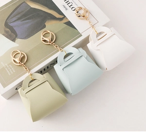 Three mini leather purse keychains in pastel green, light blue, and beige colors