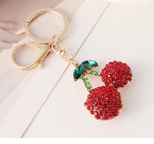 Detail of red rhinestone cherry keychain with green leaves on golden alloy base