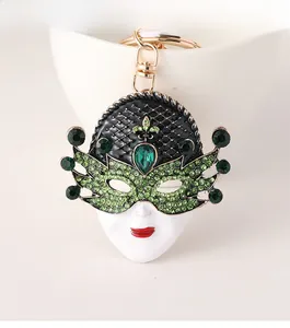 Close-up of masquerade mask keychain with green rhinestones and a gold metal clip