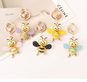 Detailed macro view of five colorful rhinestone bee keychains with golden metal bases