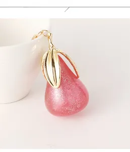 Gros plan détaillé d'un pendentif poire en résine avec paillettes roses et feuille dorée