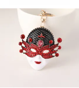 Detail of Venice mask keychain with red rhinestones and pink teardrop gem on white cup