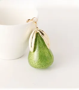 Vue détaillée du porte-clés poire avec texture en résine verte et paillettes dorées