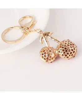 Detail of cherry keychain with golden hollow spheres and red sparkling rhinestones