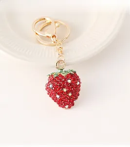 Détails des strass rouges et blancs scintillants sur le pendentif fraise doré porte-clés