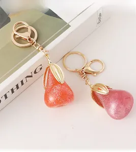 Détail de porte-clés poire en résine pailletée rose et orange avec attaches en métal doré