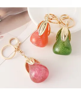 Détail de porte-clés en résine en forme de poire avec paillettes et feuilles dorées