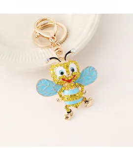 Detailed close-up of a cute rhinestone bee keychain with golden clasp on a white plate
