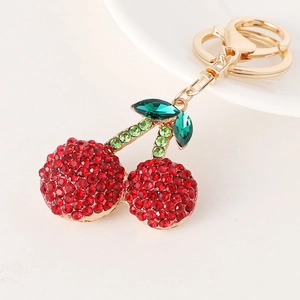 Sparkling cherry keychain with red rhinestones and golden lobster clasp on a light surface