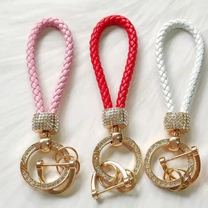 Close-up of pink, red, and white braided leather keychains with sparkling crystal-set gold hardware