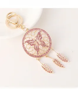 Macro detail of golden dreamcatcher keychain with pink butterfly and feather charms