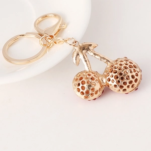 Exquisite gold cherry keychain with sparkling red rhinestones on a white porcelain plate