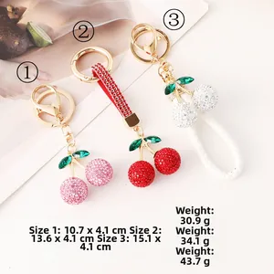 Gros plan détaillé de trois porte-clés cerise 3D avec strass en rose, rouge et blanc