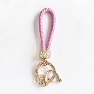 Pink braided leather car keychain with gold rhinestone-studded ring and horseshoe buckle