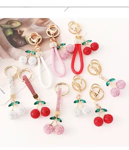 Détail de porte-clés cerise en cristal avec lanières en cuir tressé en rouge, rose et blanc
