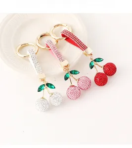 Gros plan de trois porte-clés cerise en cristal rouge rose et blanc avec lanières en cuir