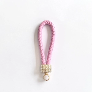 Close-up of pink braided leather keychain with sparkling rhinestone-studded gold hardware
